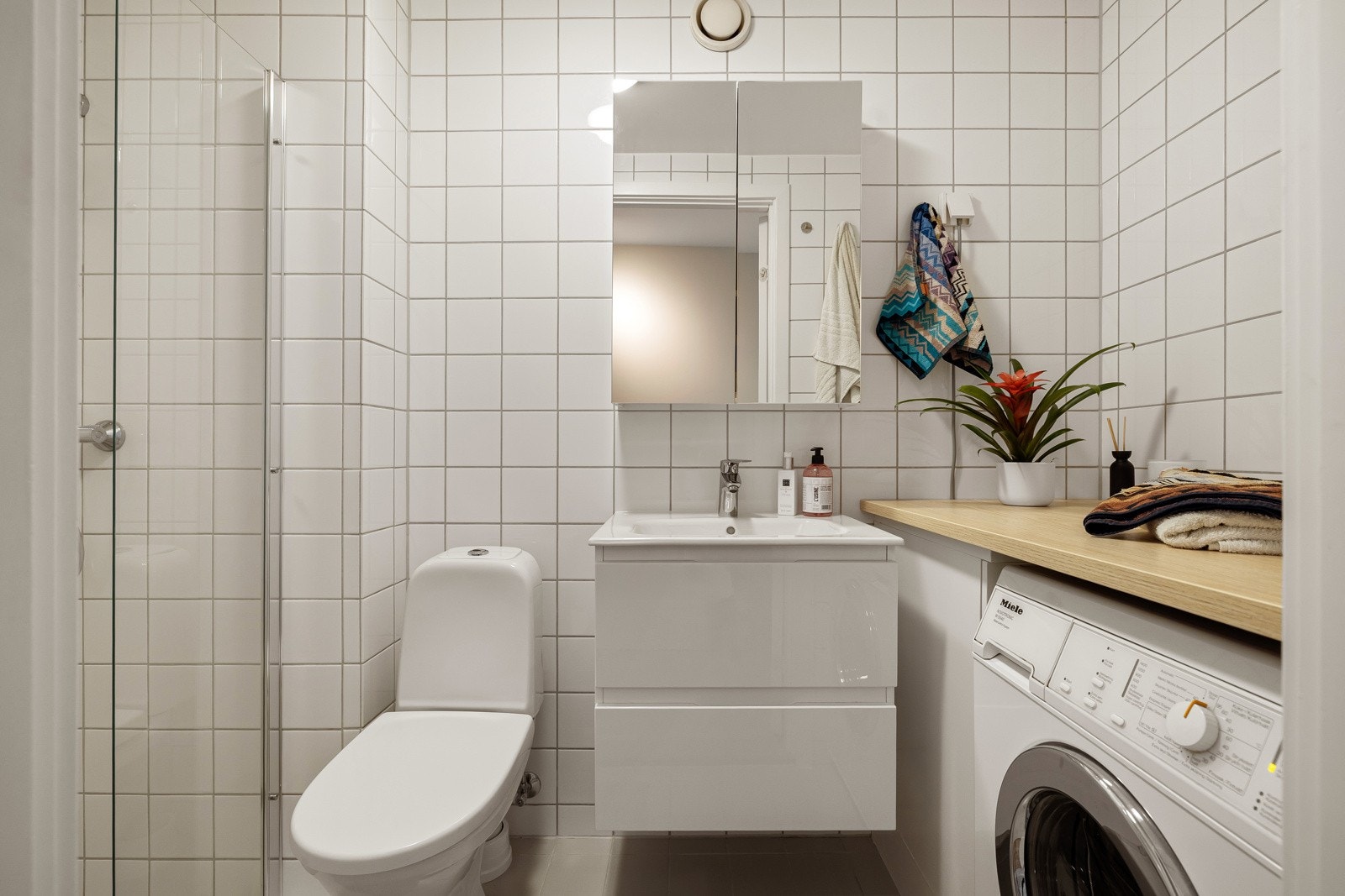 Moderne baderomsinnredning med skuffer og heldekkende servant, vegghengt speilskap over. Galleribilde