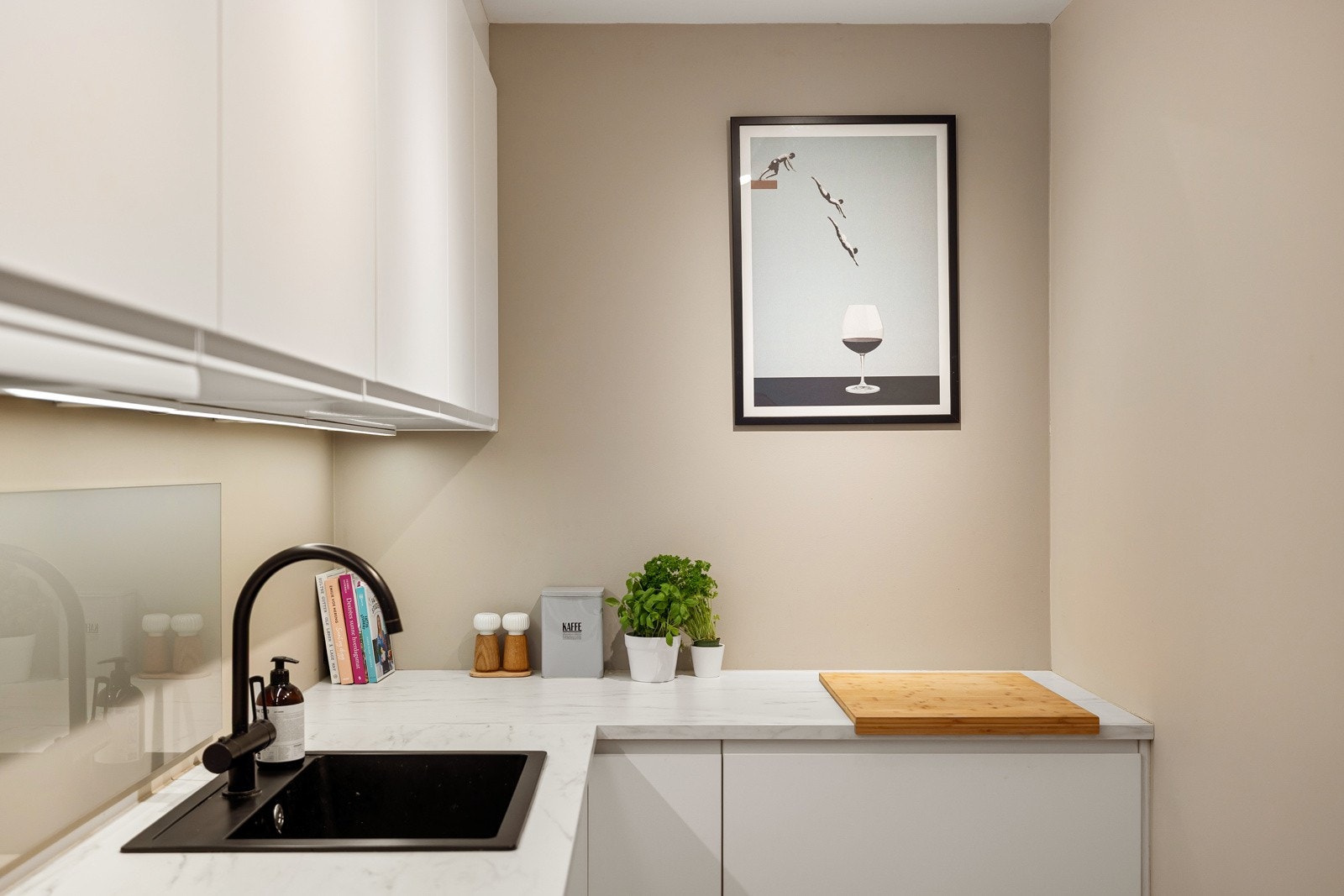 Innredningen har hvite glatte fronter og laminert benkeplate med nedfelt oppvaskkum. Praktisk med sprutplate i benkeryggen og belysning under de takhøye overskapene. Galleribilde