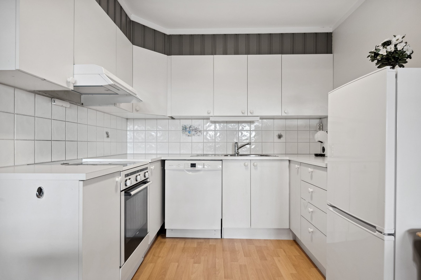 Kjøkkeninnredning med lyse, slette fronter og laminerte benkeplater. Galleribilde