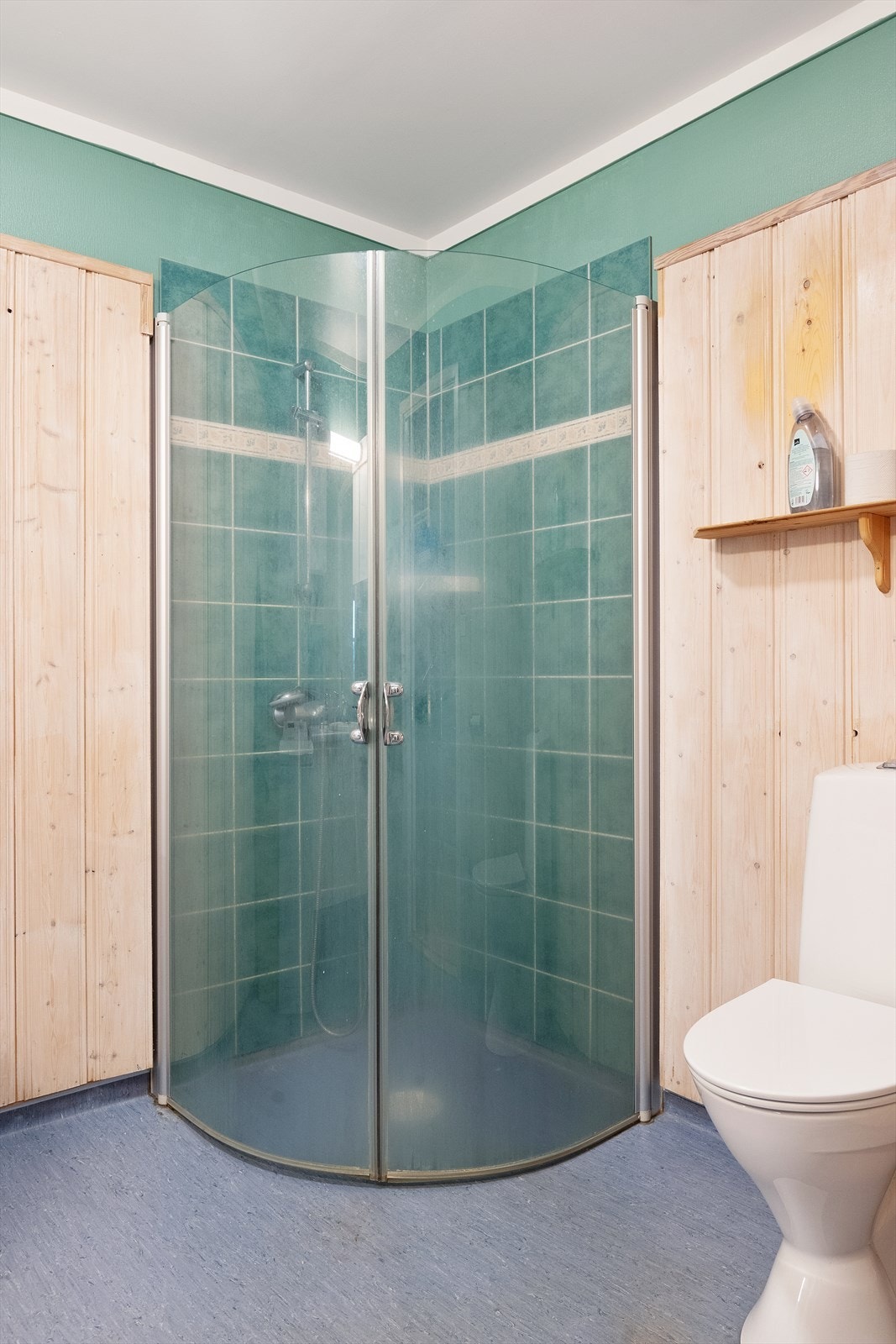 Badet har gulvmontert toalett og dusj med innfellbare glassdører. Galleribilde