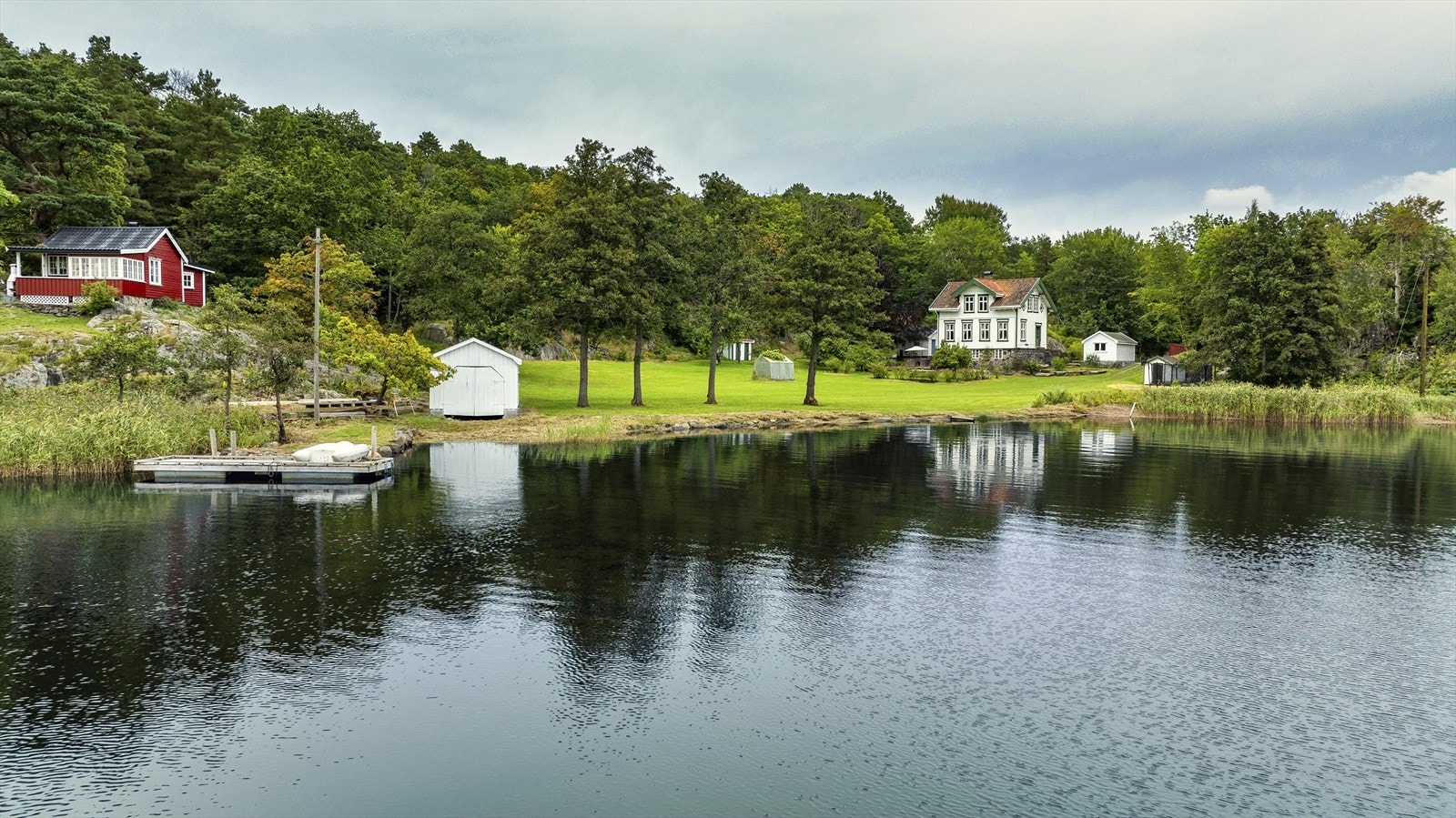 Nede ved bryggen er det 2 båthus/ sjøboder. Sjøboden til venstre for den hvite raste i storm, og det er nå kun bygget et reisverk hvor den stod. Galleribilde