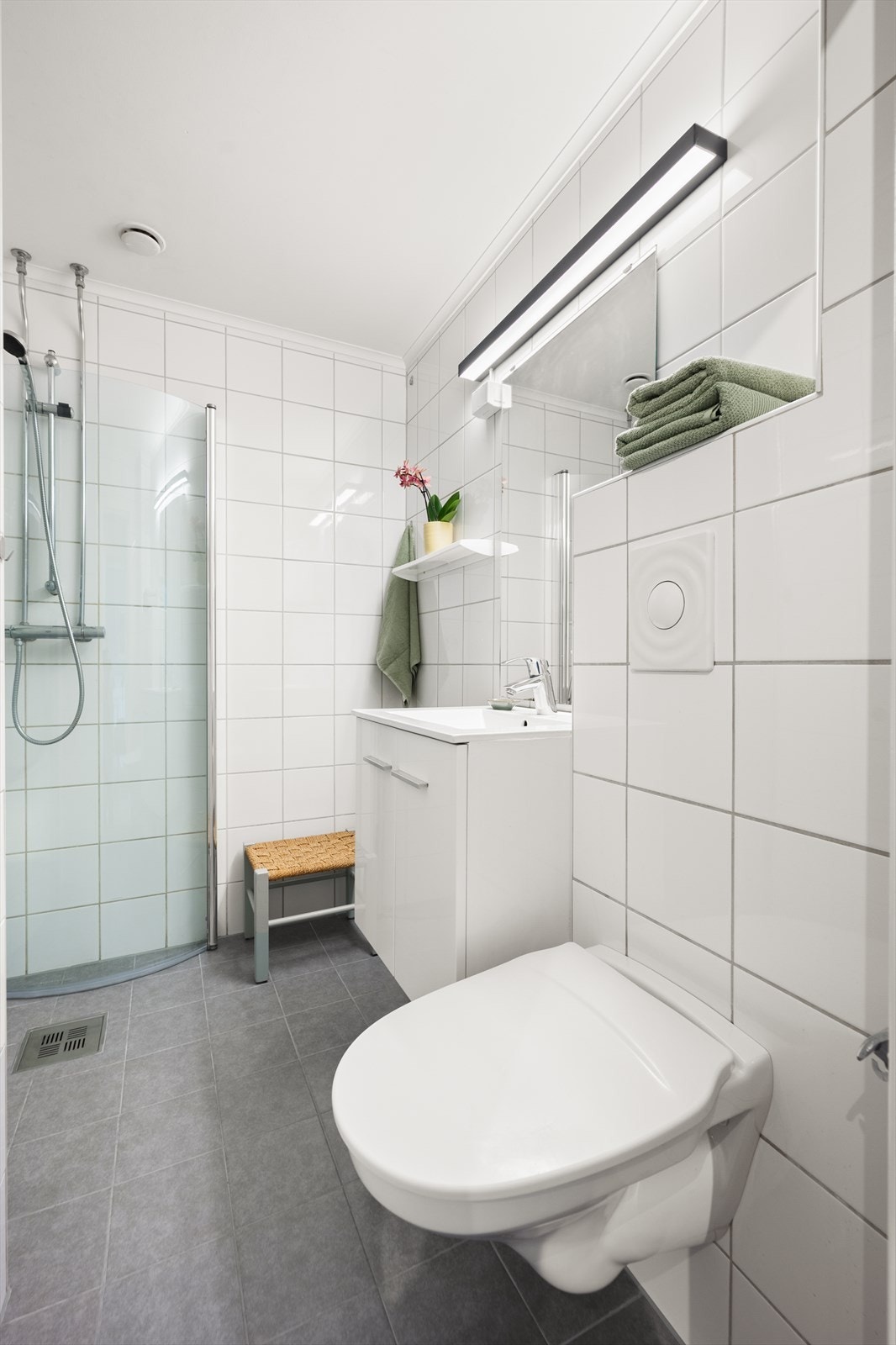 Rommet er innredet med vegghengt toalett, dusjhjørne med svingbare glassdører og baderomsinnredning med skuffer, servant nedfelt i innredning og speil. Opplegg for vaskemaskin. Galleribilde