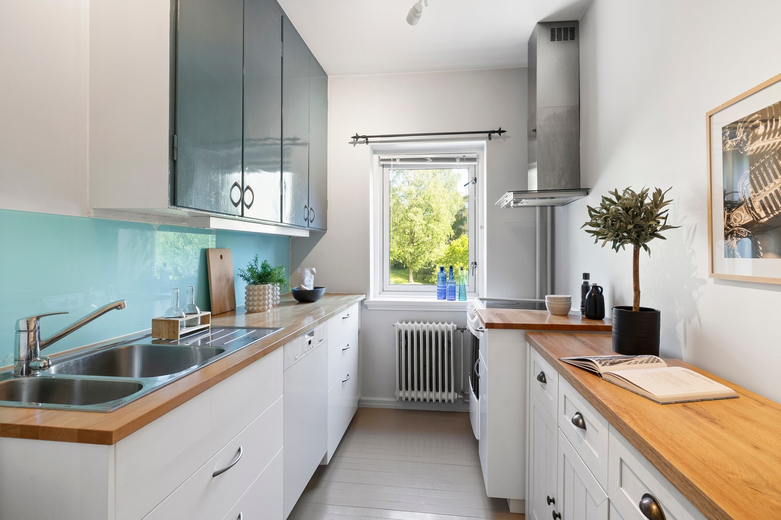 Dels IKEA kjøkkeninnredning fra 2016 med hvite/høyglansede fronter, dels overskap fra byggeåret med malte fronter. Galleribilde