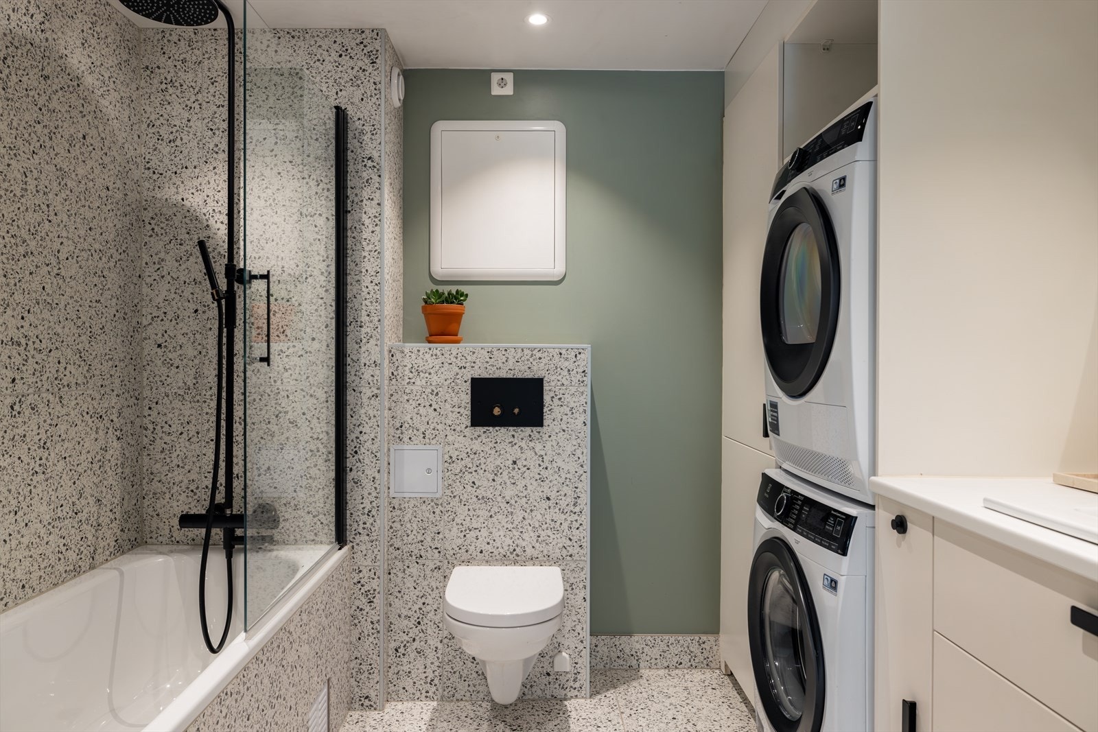 Flislagt gulv med gulvvarme, og en kombinasjon av fliser og slett vegg gir et stilrent uttrykk. Galleribilde