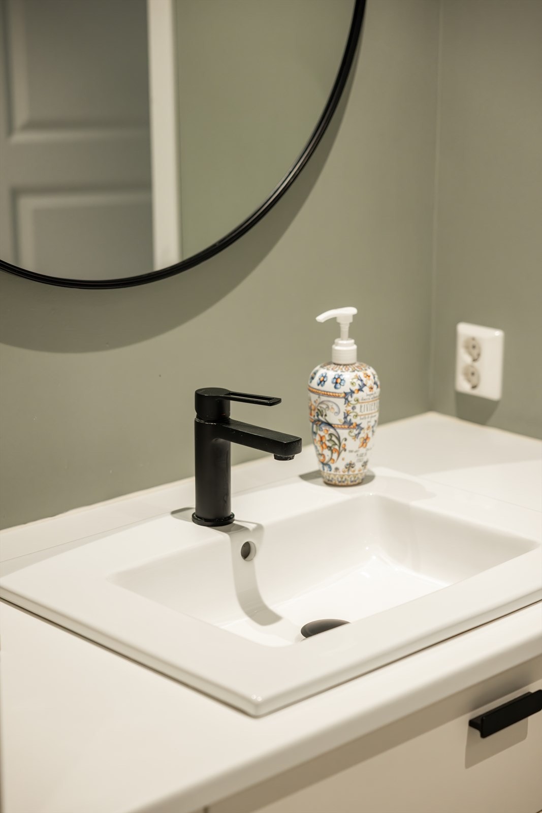 Rommet er innredet med innmurt badekar med glassdører, vegghengt toalett og servant med moderne armatur. Galleribilde