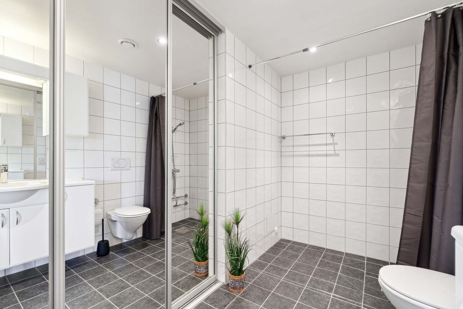 Vaskemaskin er bak skyvedører med speil på, slik at du får en forstørret romfølelse og muligheten til å fremstille badet på en ryddigere måte. Galleribilde