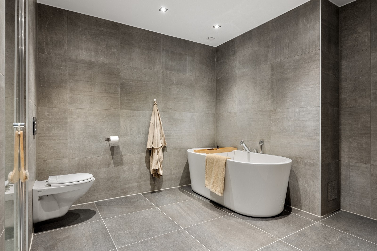 Badet inneholder et stilrikt baderomsmøbel, badekar, dusjnisje og vegghengt toalett. Galleribilde