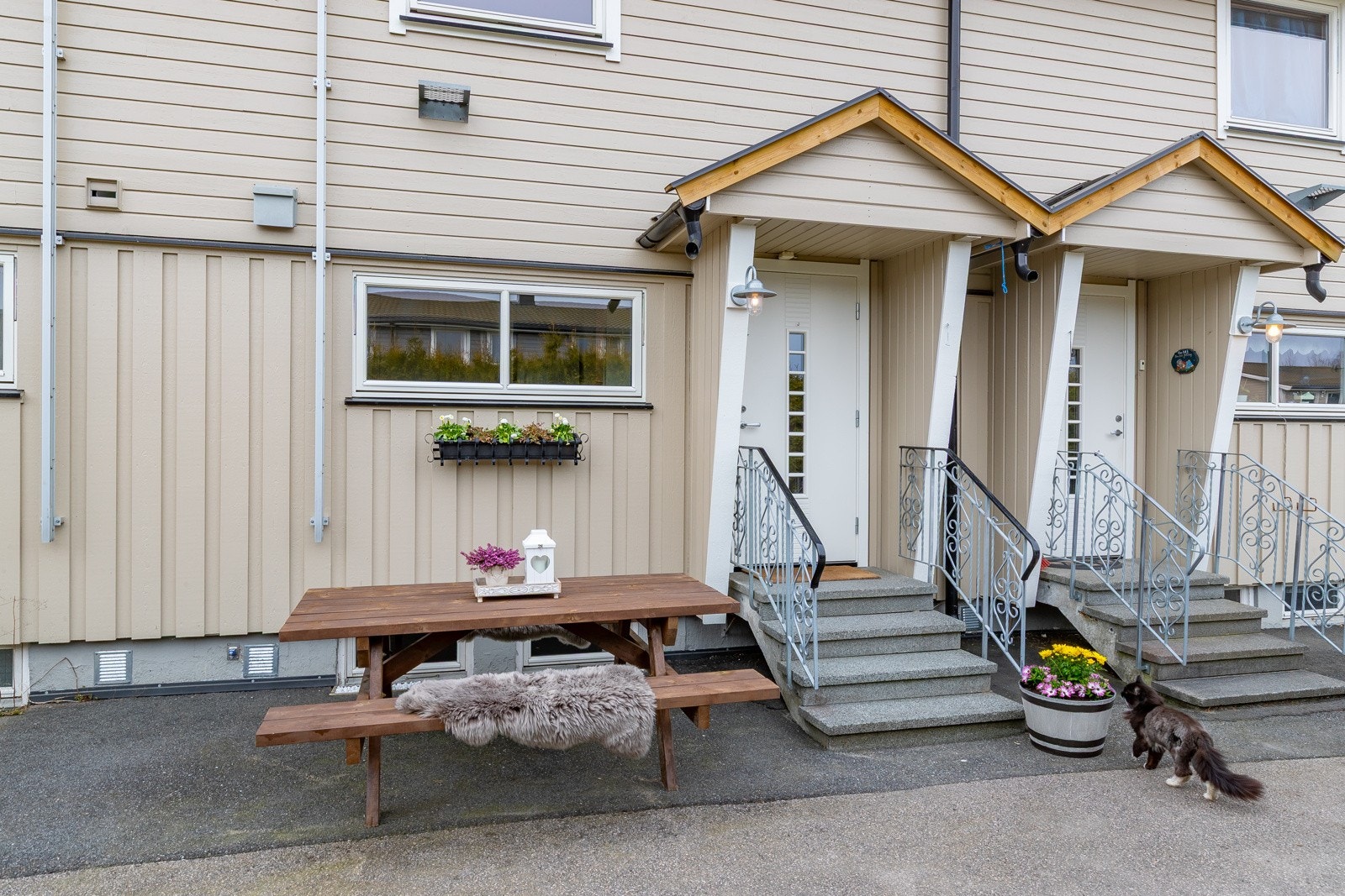 Inngangspartiet har overbygget tak over døren. Asfaltert gårdsplass. Galleribilde