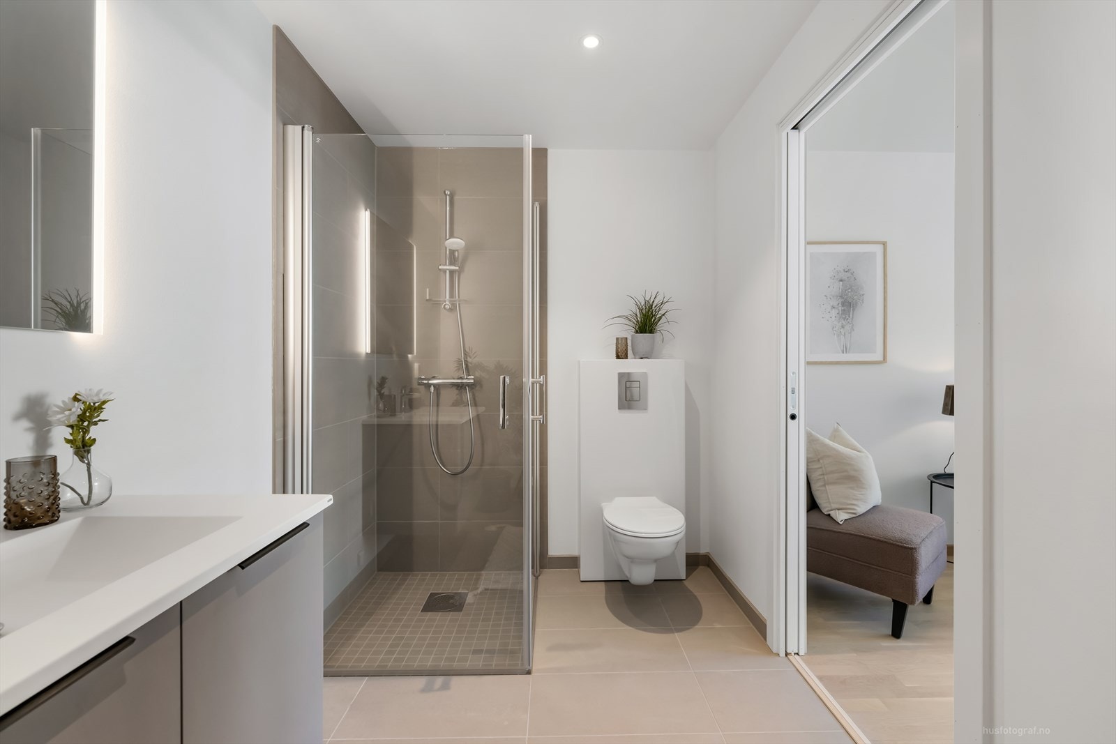 Delikat innredet bad med store 60X60 fliser på gulv i en beige fargetone og mosaikkfliser i dusj sonen. Videre har badet vegghengt toalett og dusjhjørne med innfellbare dusjvegger. Galleribilde
