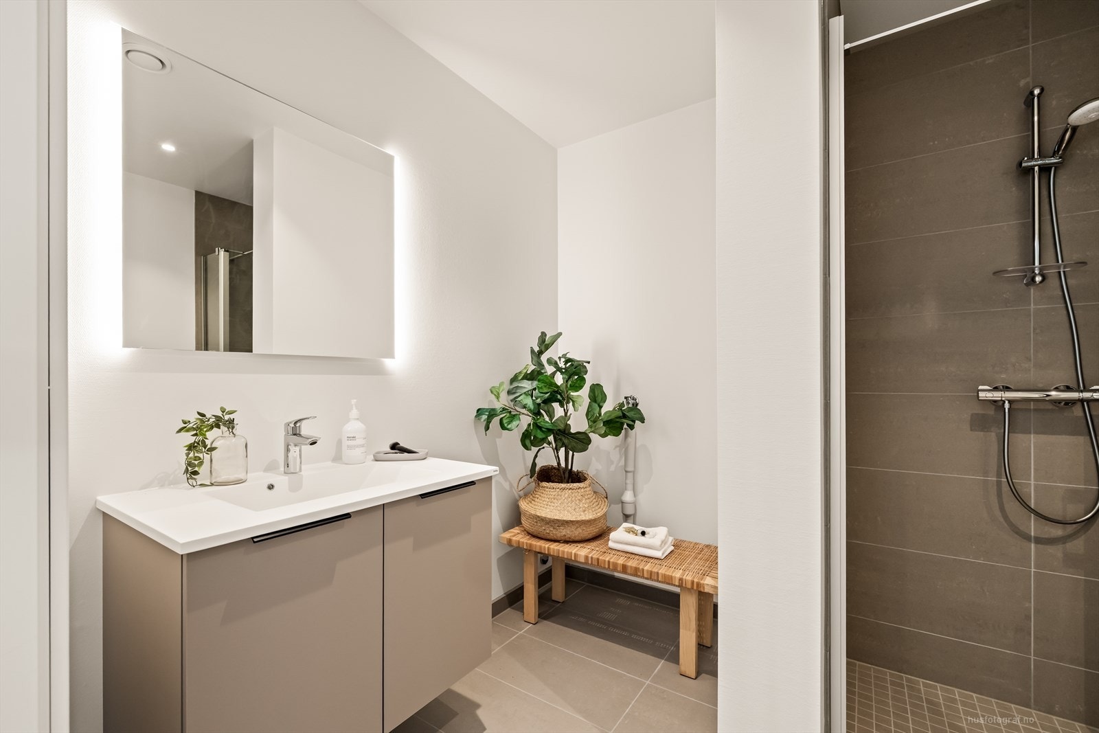 Delikat innredet bad med store 60X60 fliser på gulv i en beige fargetone og mosaikkfliser i dusj sonen. Galleribilde