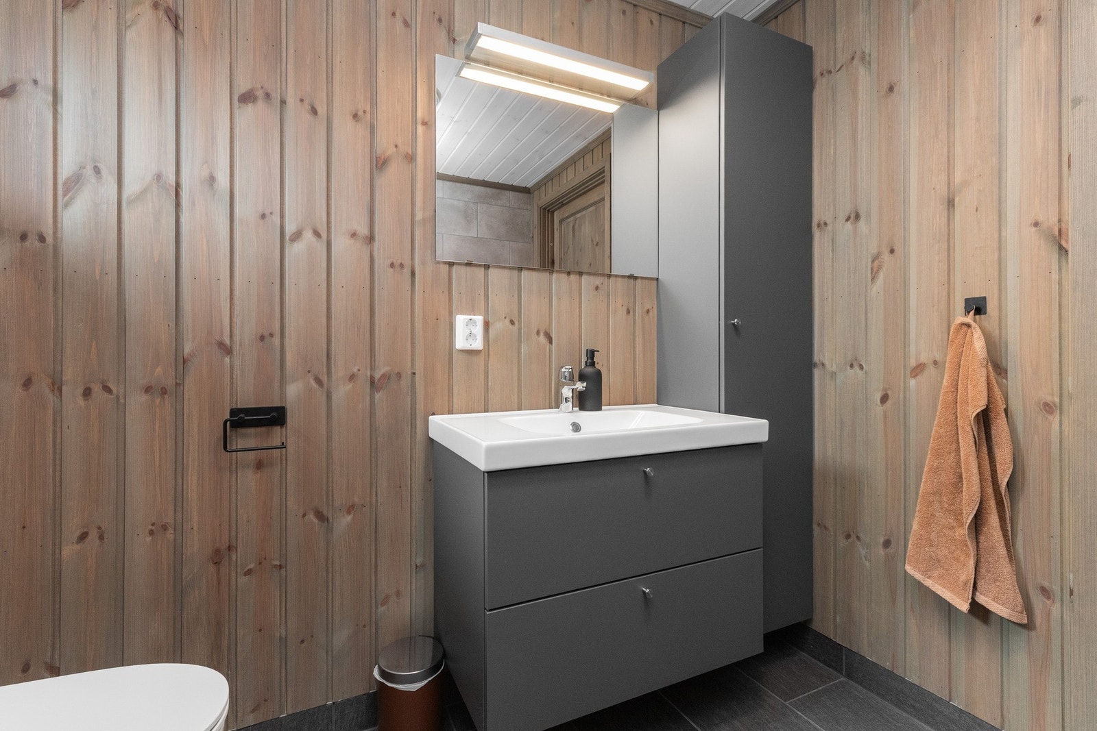 Innredet med dusjhjørne, toalett, servant med underskap og høyskap ved siden av. Galleribilde