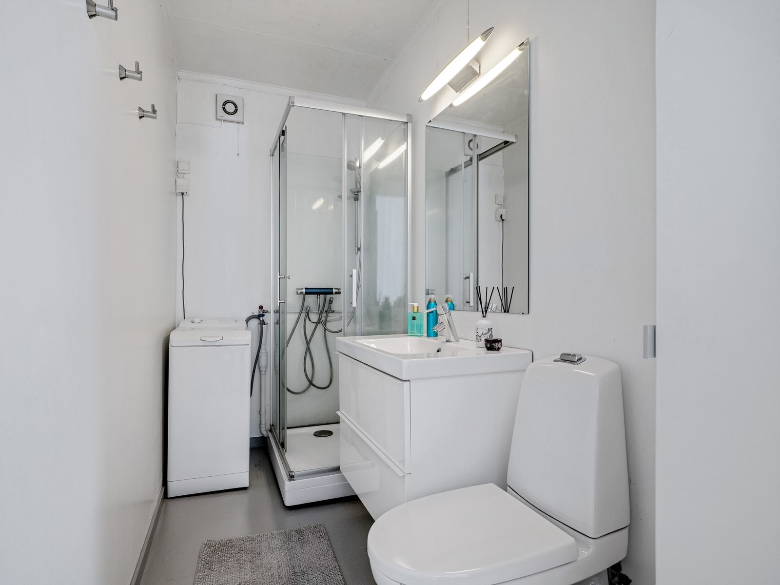 Bad i 1.etasje innredet med dusjkabinett, servant på innredning og toalett. Galleribilde