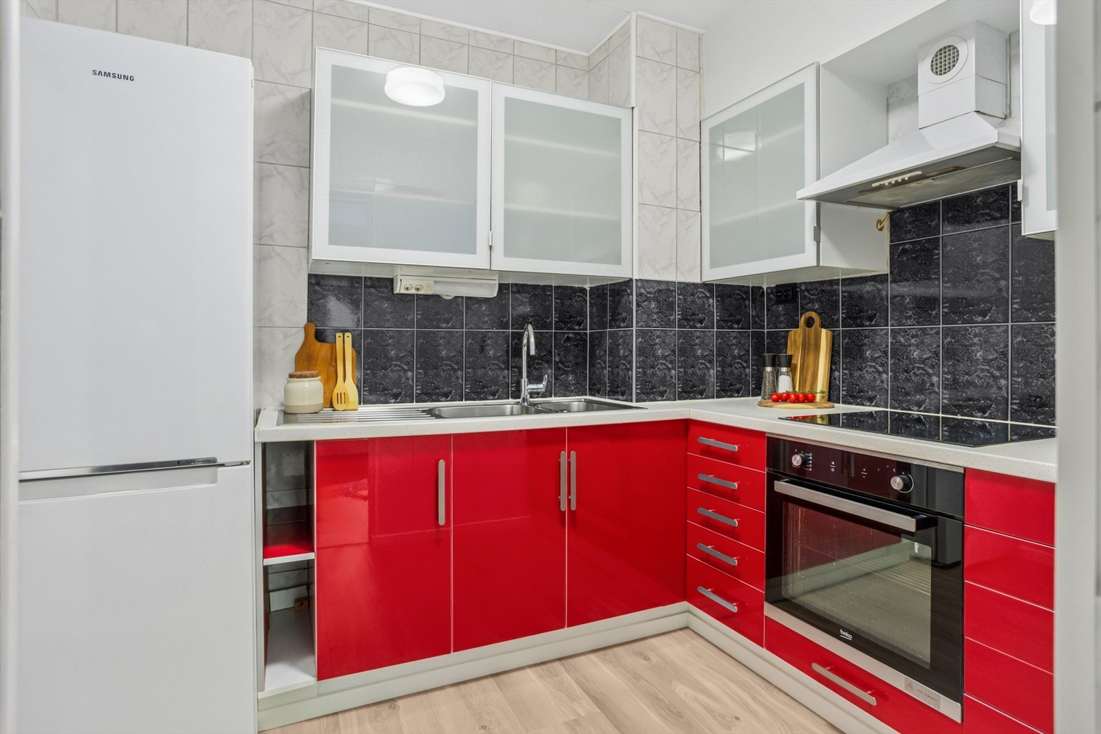 Kjøkkeninnredning fra IKEA med slette fronter og laminert benkeplate. Kjøkkenet er utstyrt med integrert komfyr og platetopp, samt frittstående kjøleskap. Galleribilde