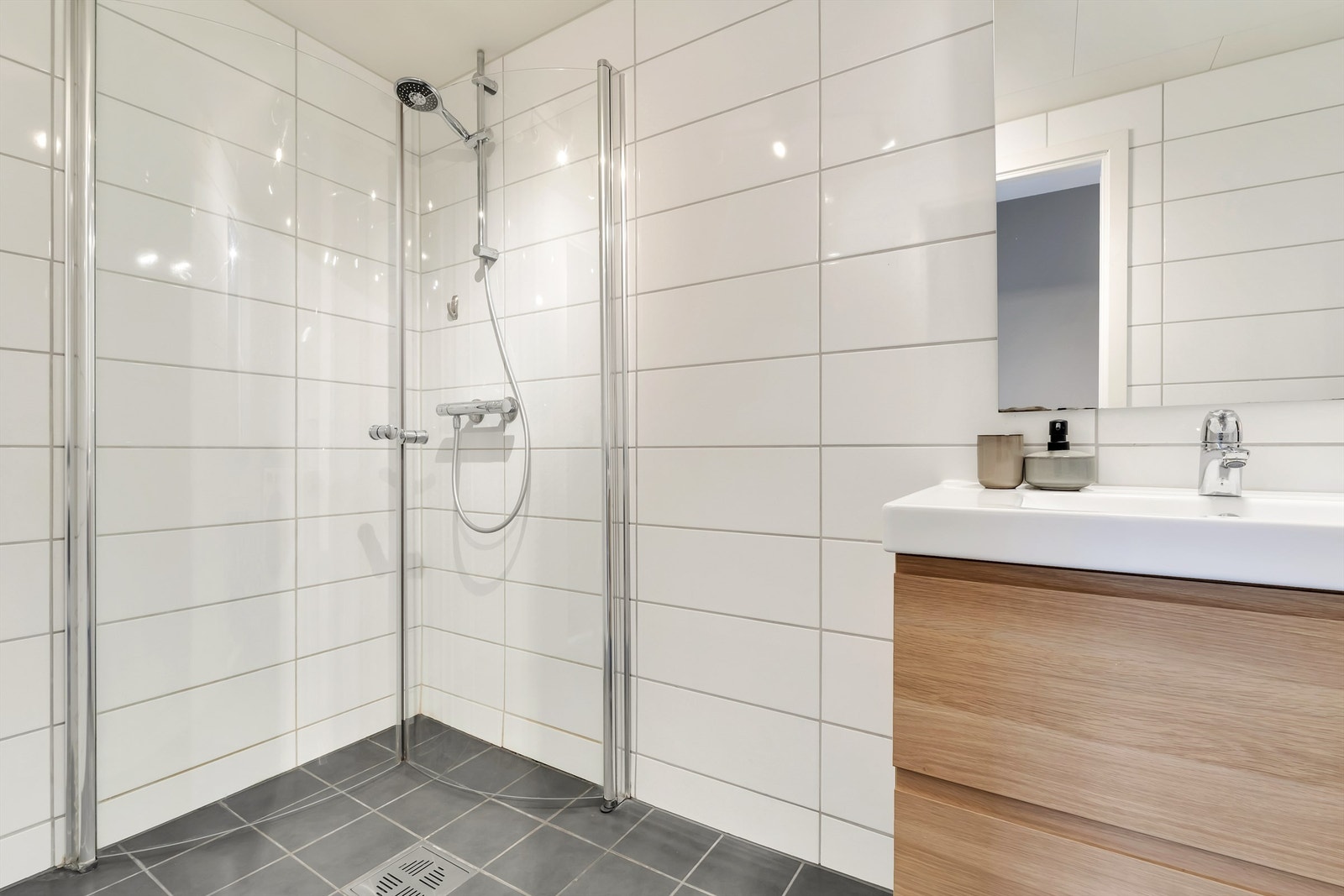 Pent fliselagt bad fra 2012 med vegghengt servantinnredning, og dusjhjørne med glassdører. Galleribilde