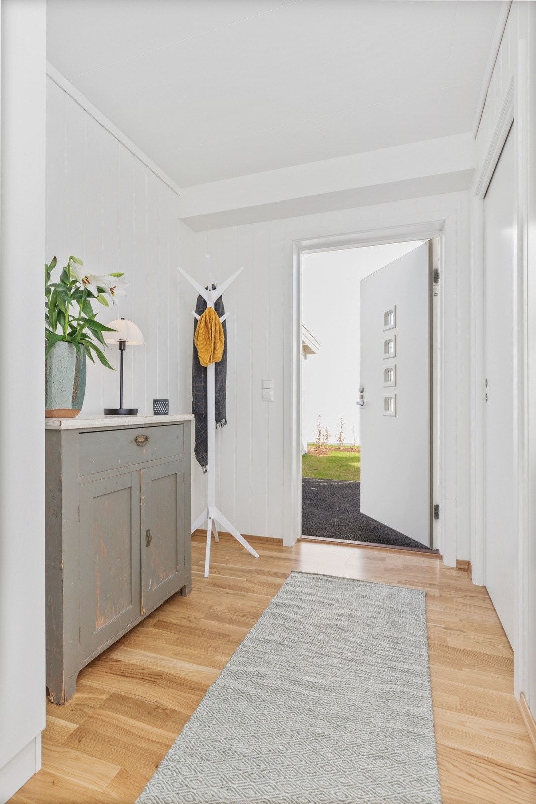 Velkommen inn! Hyggelig entre med plass til ønsket oppbevaringsmøblement til oppheng av sko og jakker. Her er det parkett på gulv og malt MDF-plater på vegger. Galleribilde