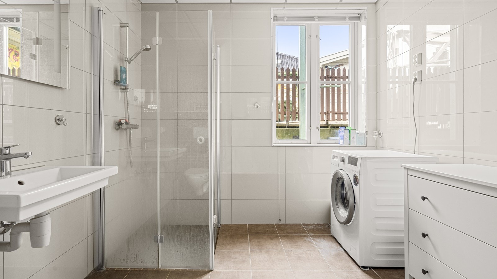 Lyst og fint bad med opplegg for vaskemaskin og god plass til møblement for oppbevaring Galleribilde