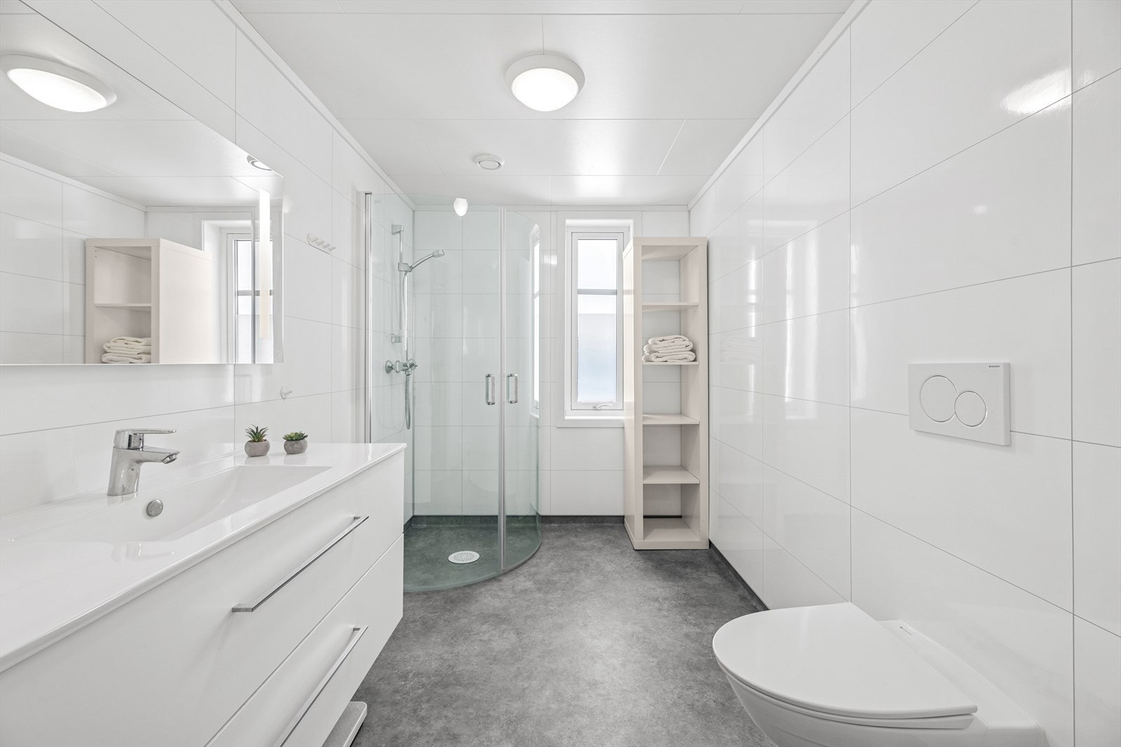 Pent baderom med belegg på gulv, plater på vegg og en romslig baderomsinnredning med god plass til håndklær og personlige eiendeler. Galleribilde