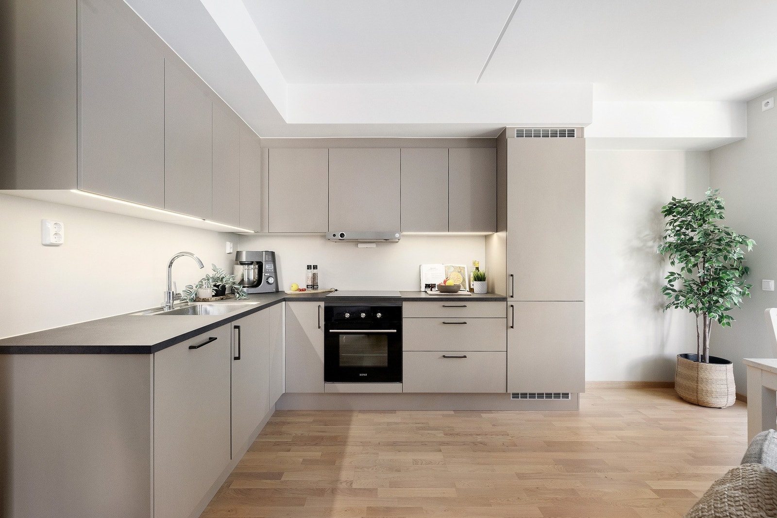 Kjøkkenet har integrerte hvitevarer som komfyr, platetopp, kjøleskap, oppvaskmaskin og ventilator over kokesone. Galleribilde