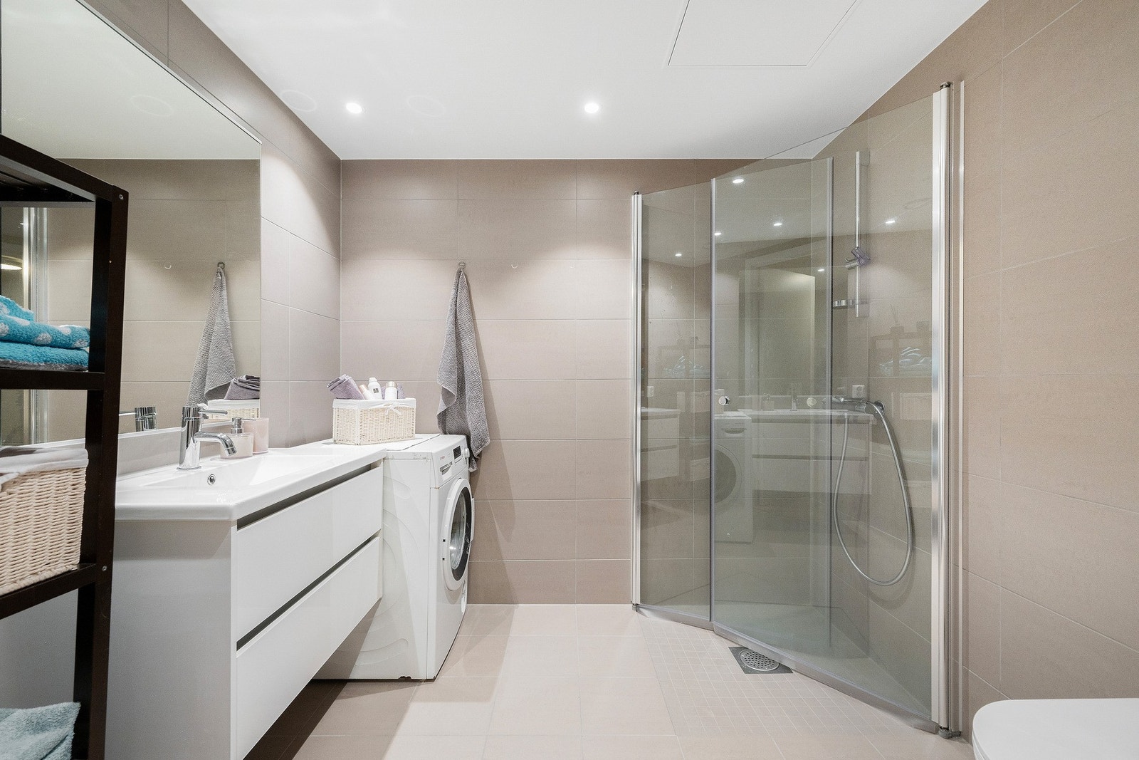 Et lunt og delikat baderom fra 2024 med flislagte flater og downlights i taket. Galleribilde