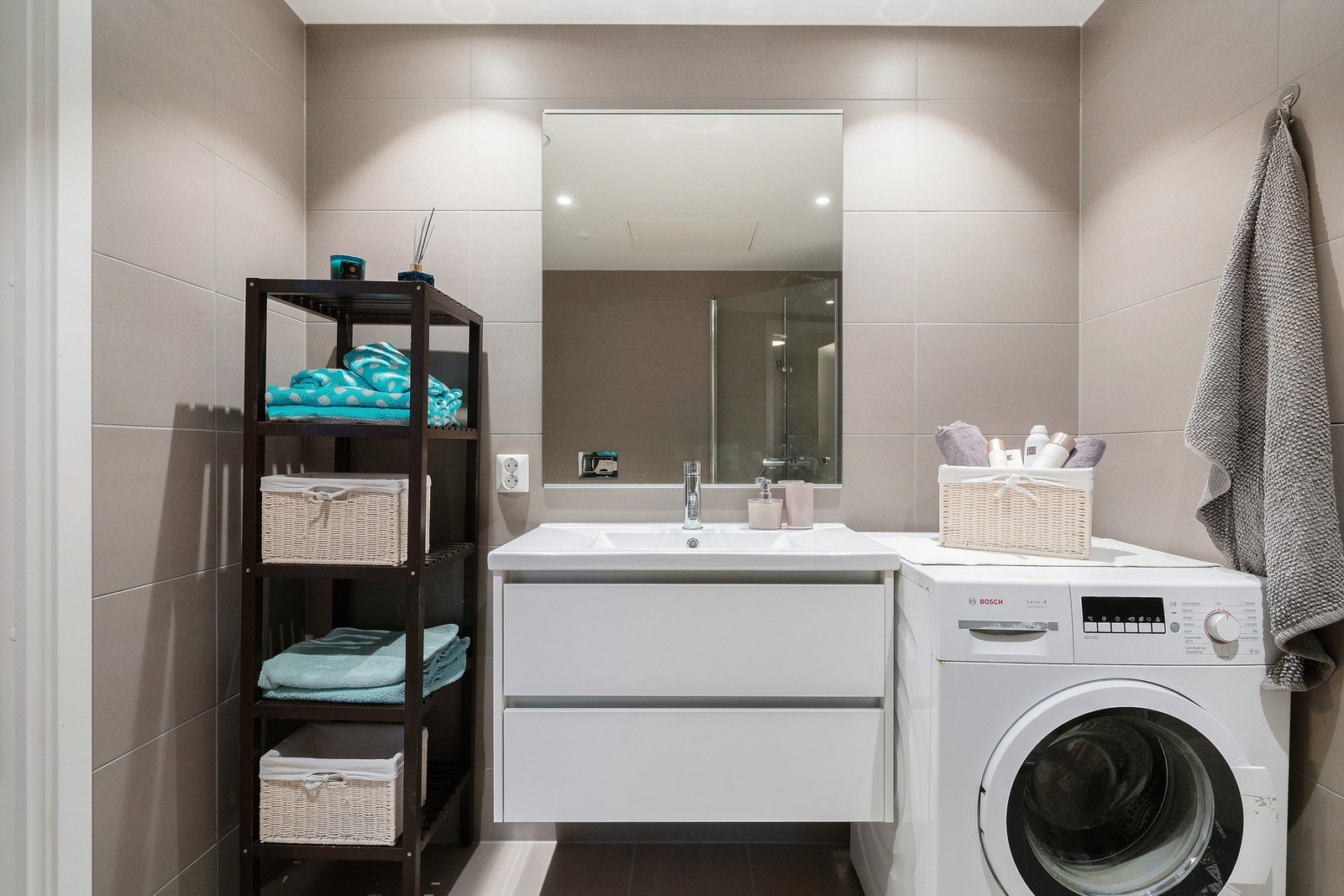 Badet er innredet med dusjhjørne med innfellbare glassdører, servant, vegghengt toalett, speil og opplegg for vaskemaskin. Galleribilde