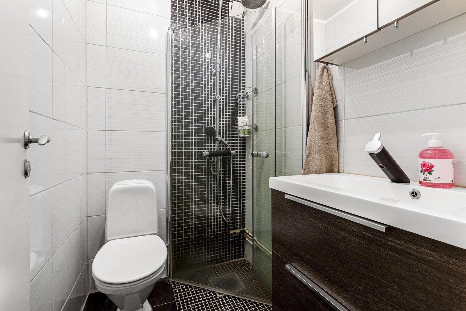 Det er mørke fliser på gulv og deler av veggen i dusjsonen, noe som står i fin kontrast til resten av badet Galleribilde