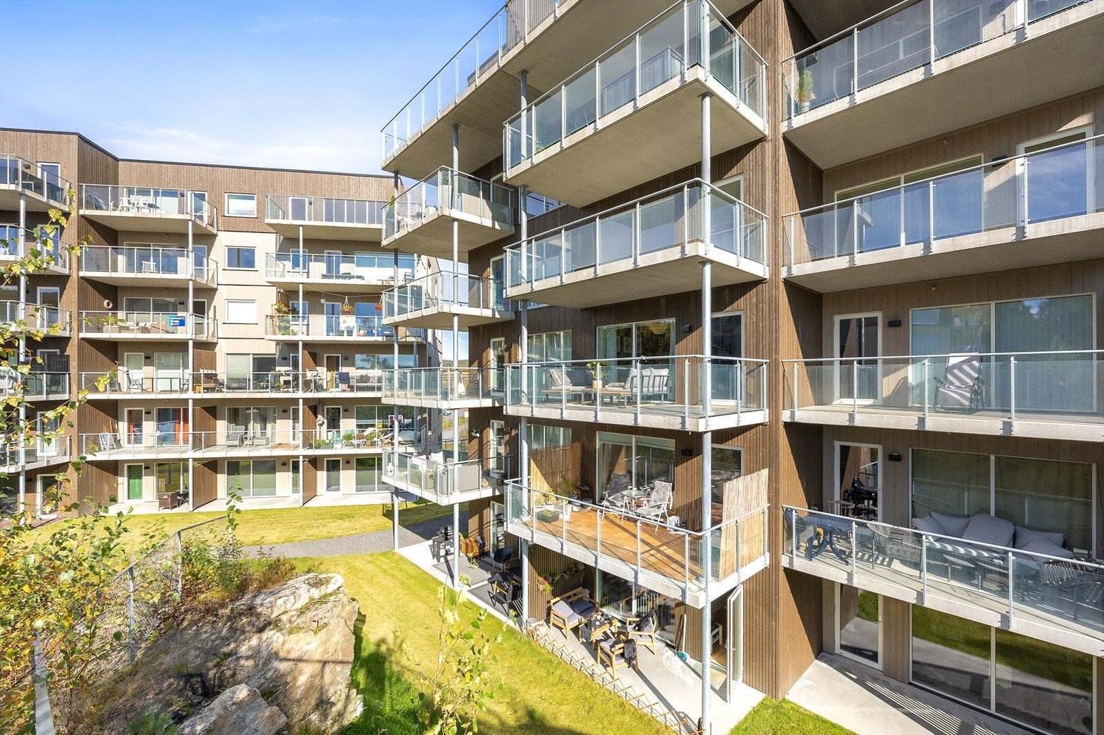 Fasade med balkonger. Felles eiet tomt for sameiet som er pent opparbeidet med plenareal, beplantning, vei og parkeringsareal. Galleribilde