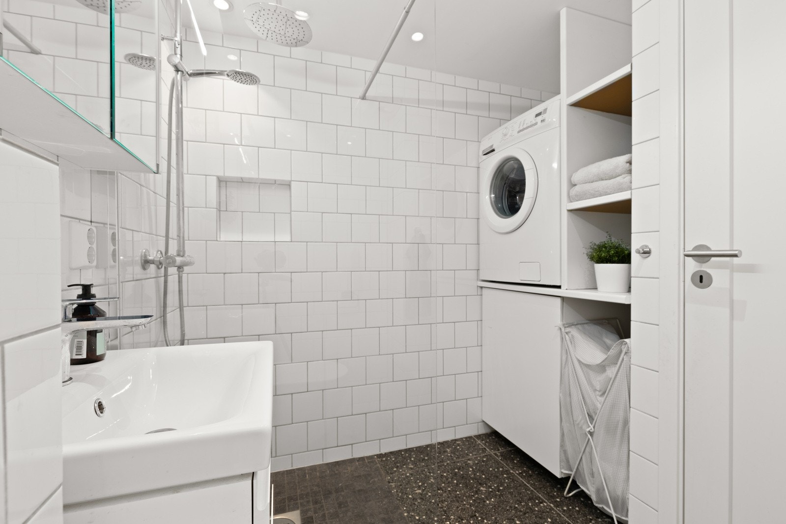 Videre har badet et separat dusjhjørne med regnfallsdusj og glassvegg. Det er laget en praktisk plassbygd hylleløsning i vegg m/egen plass for vaskemaskin. Galleribilde