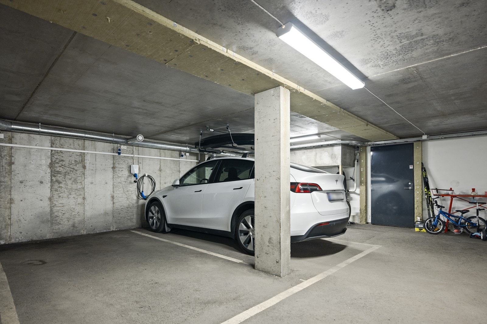 Til boligen medfølger to garasjeplasser med elbillader. Det er direkte adkomst til garasjeanlegget via sluse i underetasje hvorpå de to plassene nærmest døren følger Galleribilde