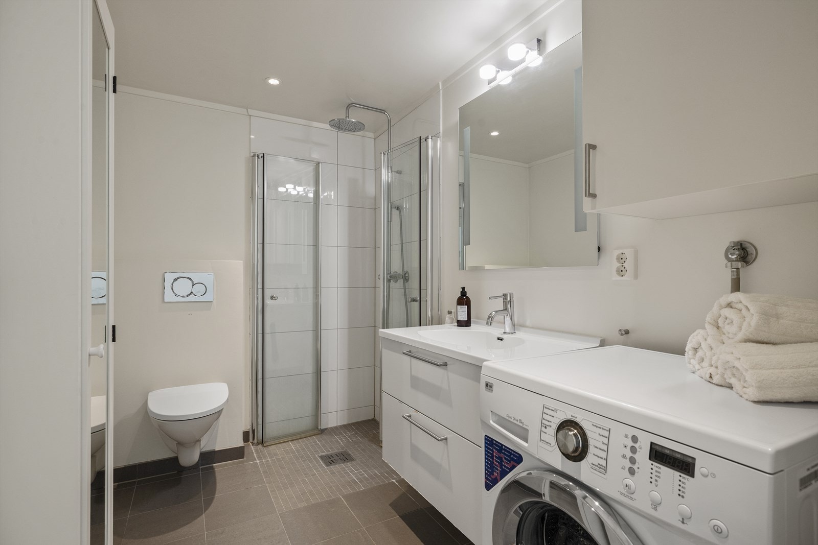 Bad med opplegg for vaskemaskin. Badet har flislagt gulv med elektriske varmekabler og malte veggflater Galleribilde