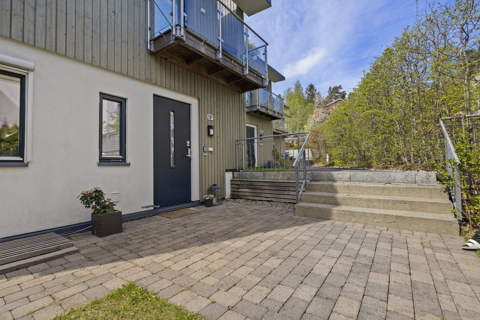 Boligen har adkomst via et pent opparbeidet inngangsparti med belegningsstein, beplantning og plass til sittegruppe Galleribilde