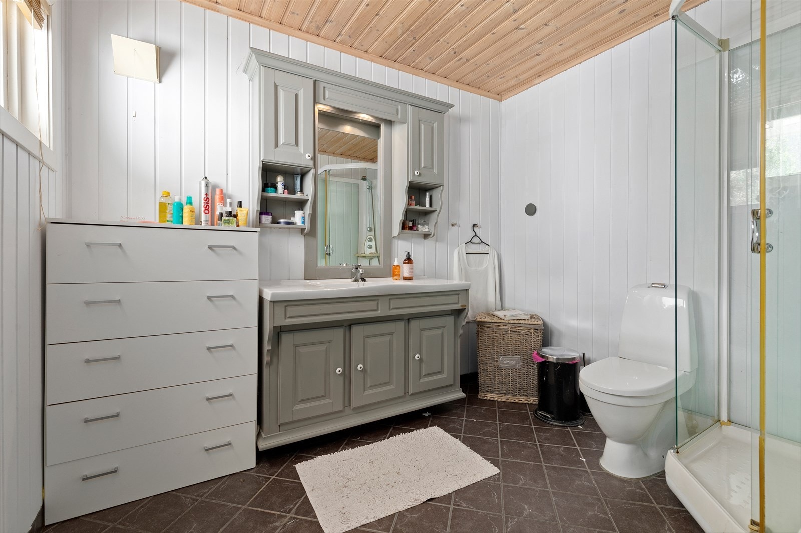 Lys bad med fliser på gulv. Heldekkende servant og gulvstående toalett Galleribilde