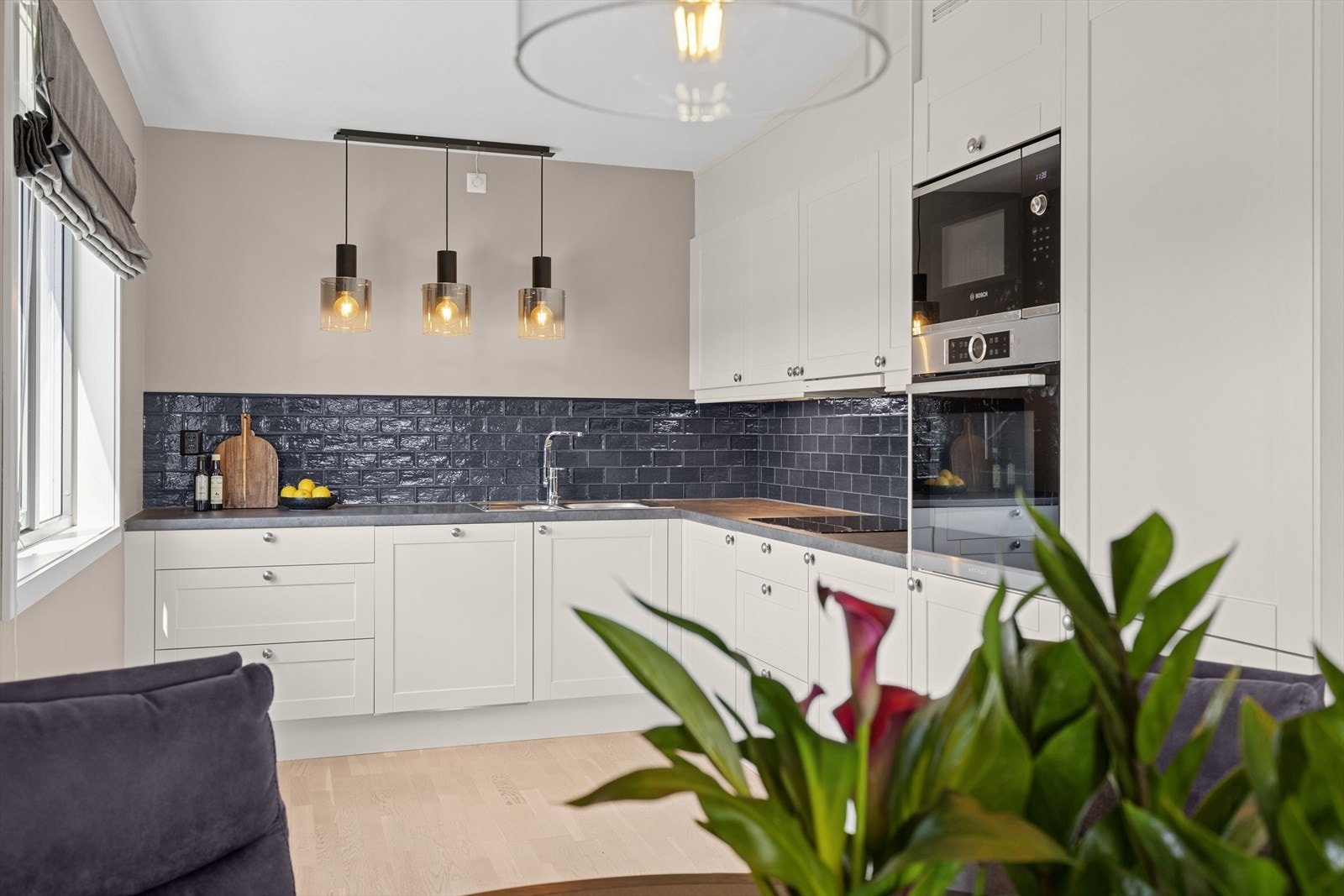 Delikat kjøkken med hvite profilerte fronter og laminat benkeplate med oppvaskkum samt fliser på vegg over benk. Galleribilde