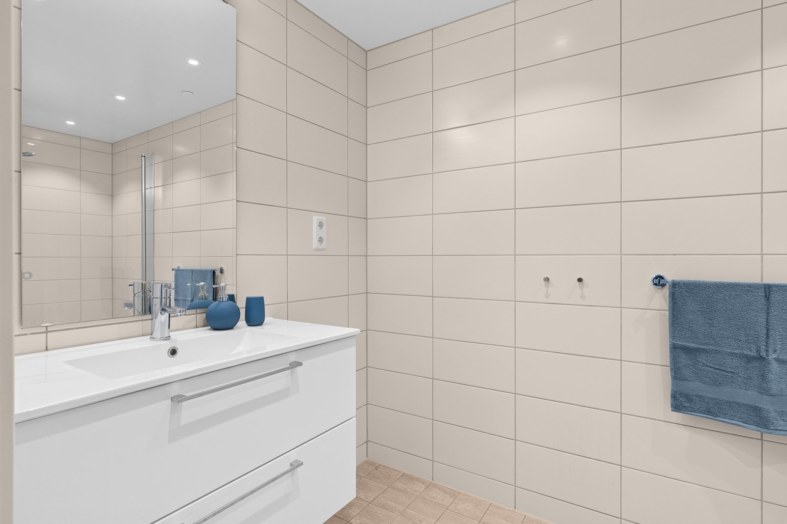 Badet er innredet med veggmontert wc, servantinnredning, dusjvegger og plass for vaskesøyle. Galleribilde