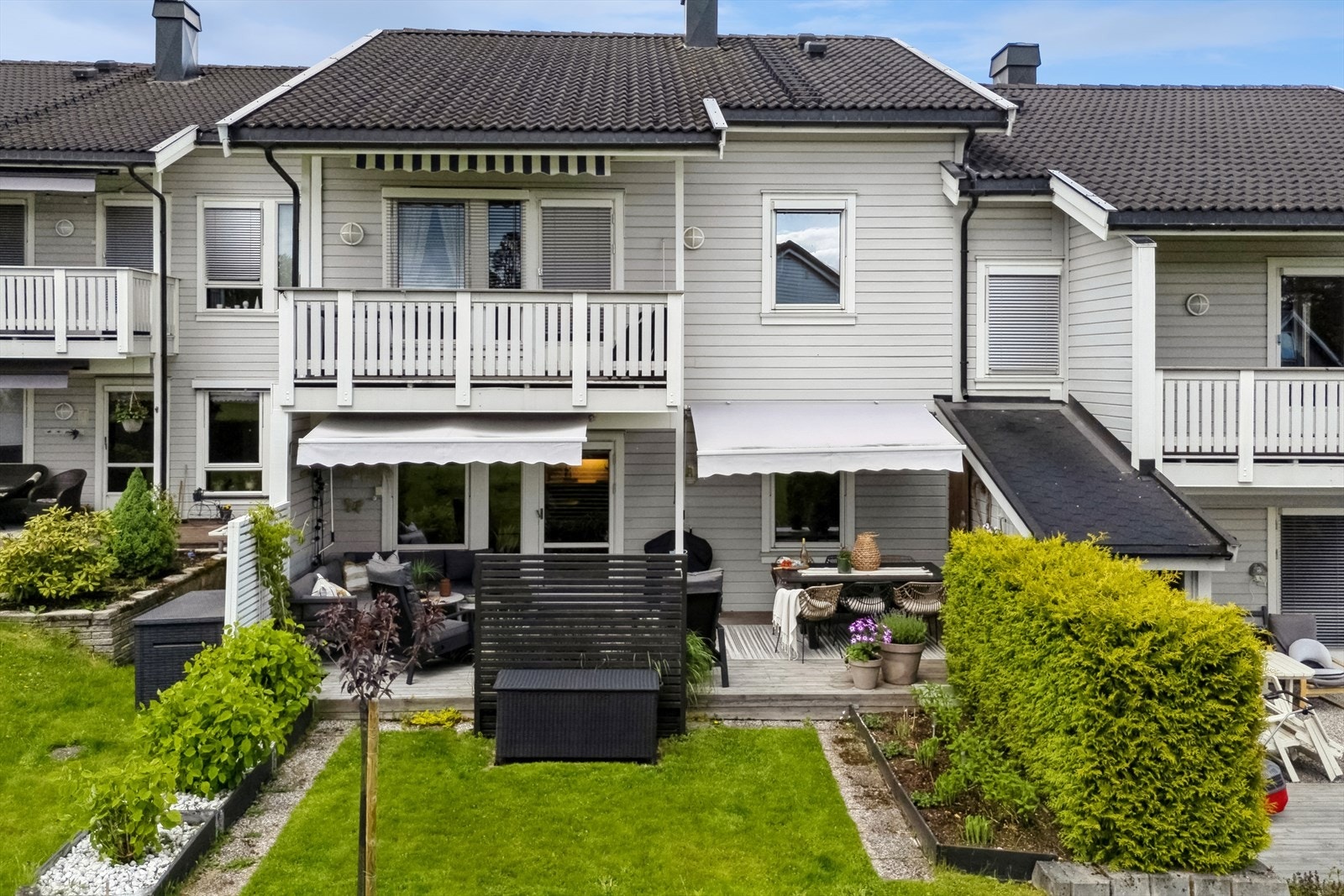 Hagen rammes inn av hekk og opphøyde bed, og terrassen skjermes av levegger på sidene og to markiser. Galleribilde