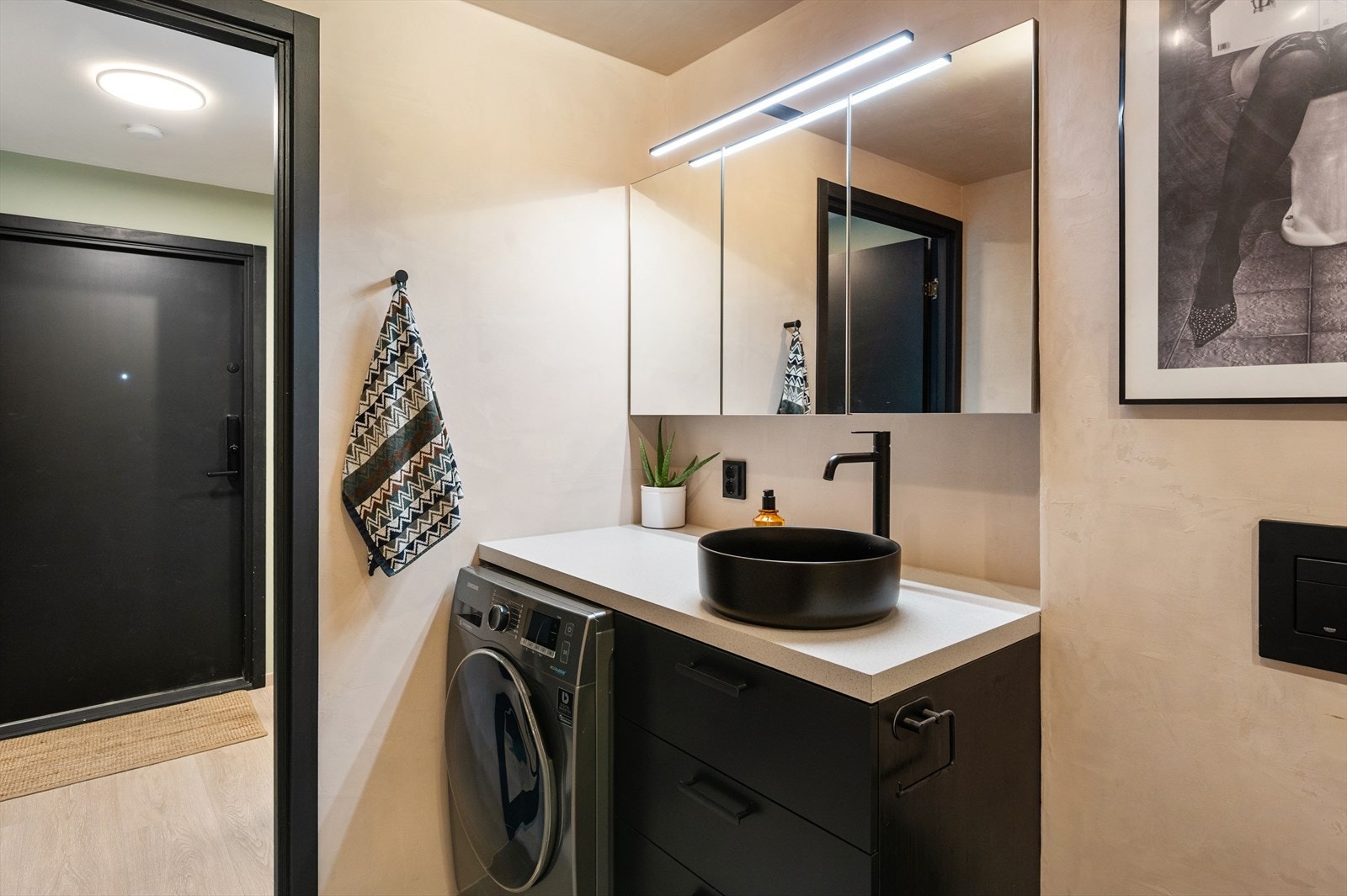 Badet er utstyrt med vegghengt toalett, servant med underskap, speilskap med lys og dusjhjørne med glassfelt. Galleribilde