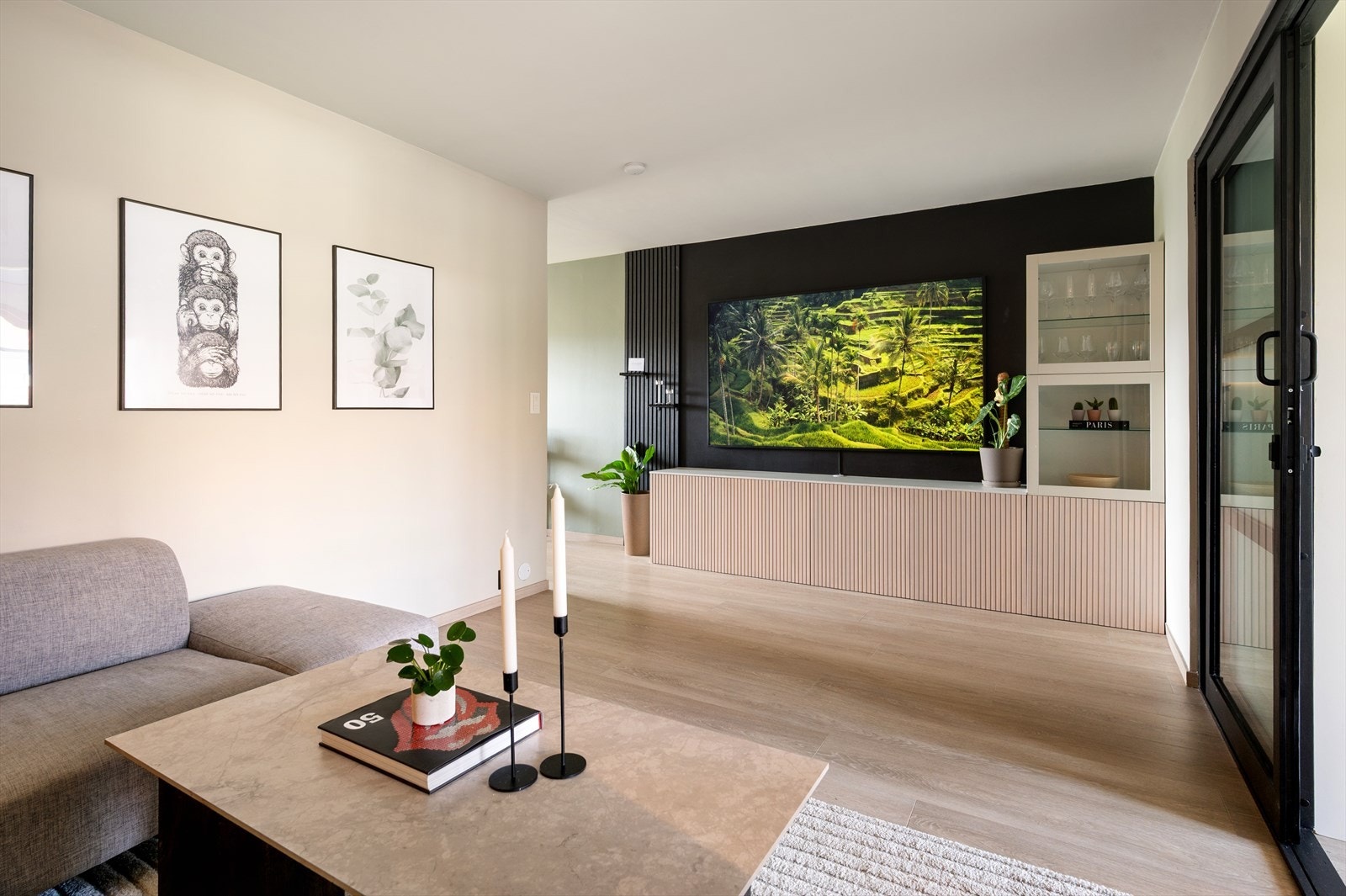 Langs den ene veggen er det montert praktisk oppbevaringsskap og TV-vegg i kontrastfull sort. Galleribilde