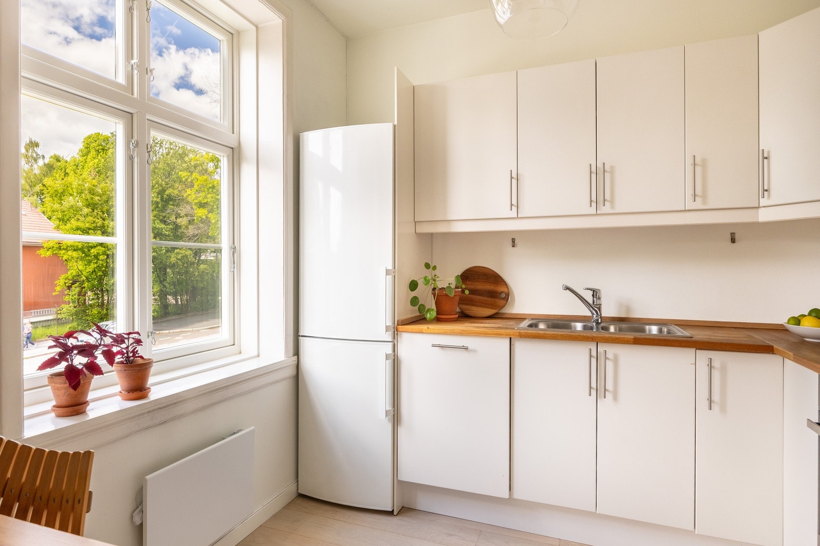 Lyst kjøkken med slette fronter og benkeplate av tre med nedfelt oppvaskkum. Galleribilde