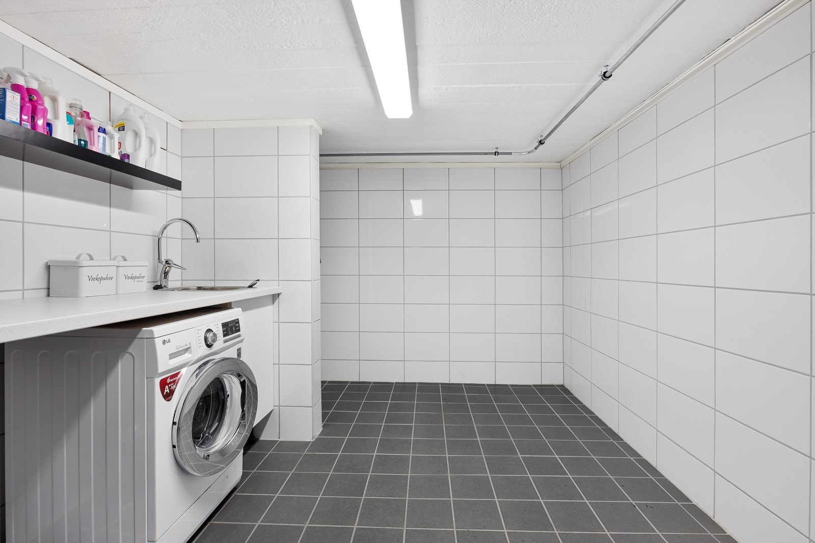 Det er pent flislagt dusjbad og vaskerom i boligens underetasje. Galleribilde