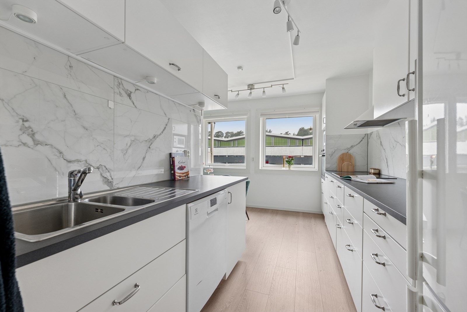 Kjøkkenet har glatte, fabrikklakkerte fronter og en slitesterk laminatbenkeplate med nedfelt kum i rustfritt stål. Galleribilde