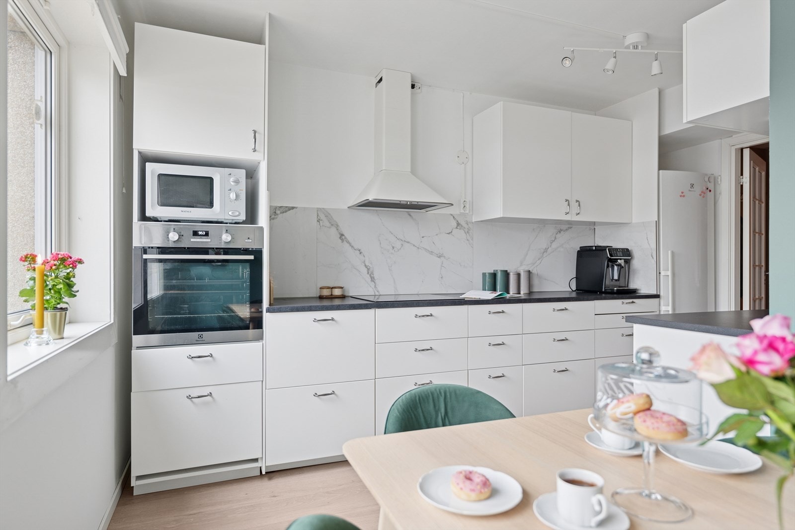 Her får du et kjøkken som kombinerer moderne design med praktiske løsninger og en sosial sone for hyggelige måltider. Galleribilde