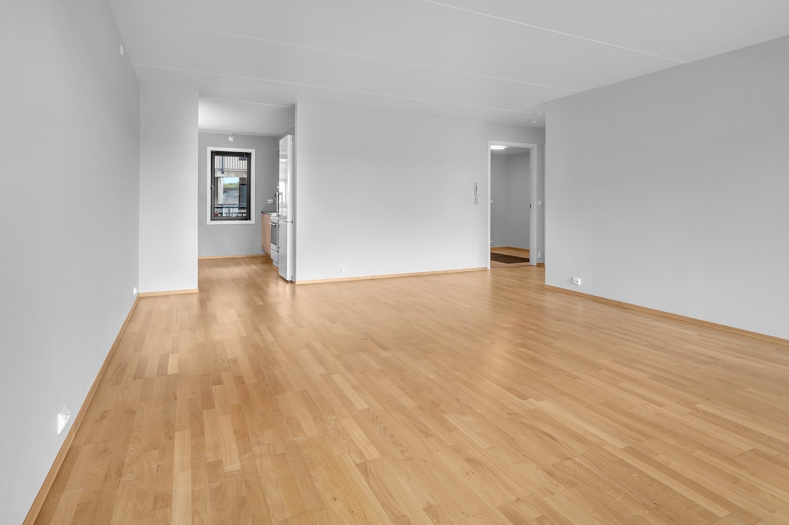Tilbake i stuen. Som man ser, gjennomgående lyse farger i vegger og tak og godt med stikkontakter. I forlengelsen av stuen finner vi kjøkkenet. Galleribilde
