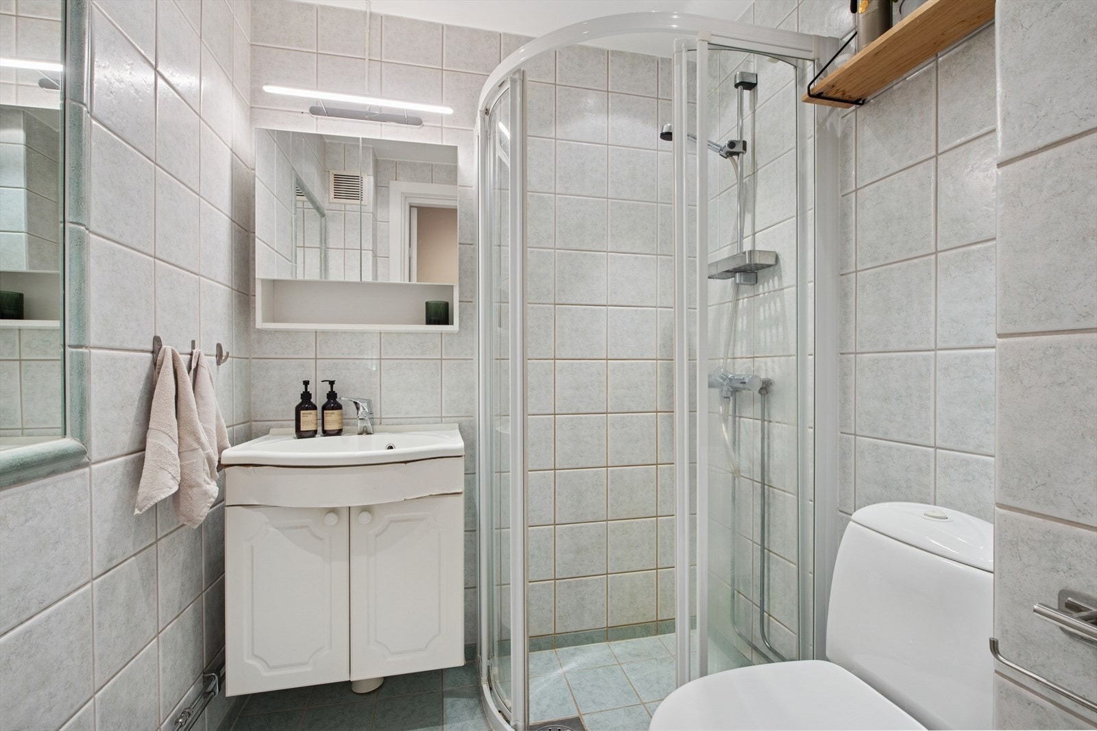 Bad modernisert i regi av borettslaget i 2001, med fliser på gulv og vegger, standard innredning, gulvvarme og dusjhjørne. Galleribilde