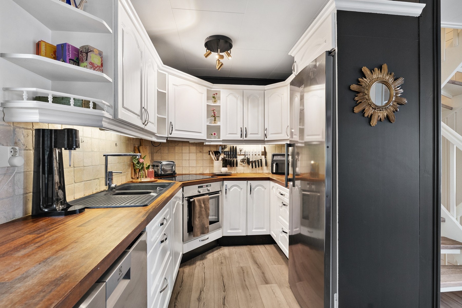 Kjøkkeninnredningen har fronter i finert slett utførelse og fliser montert under overskap. Kjøkkenet er utstyr med nedfelt servant, integrert komfyr, oppvaskmaskin og plass til kjøleskap. Galleribilde