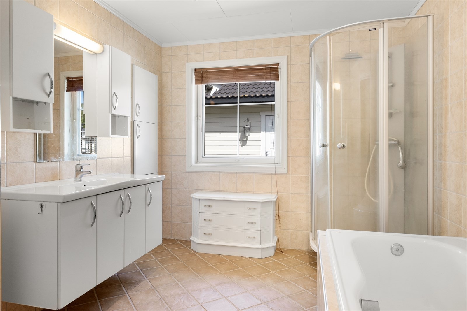 Pent bad innredet med toalett, badekar, dusjhjørne og servant på innredning. Galleribilde