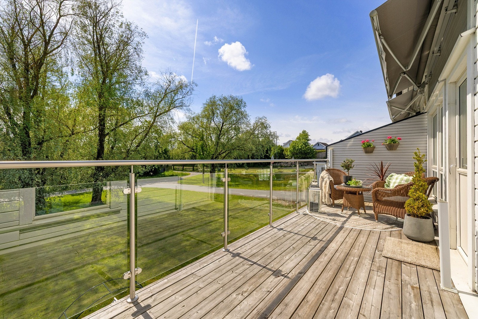 Omfangsrike gressplener og velvoksne løvtrær foran balkongen er et pent skue å hvile blikket på sommerstid. Galleribilde