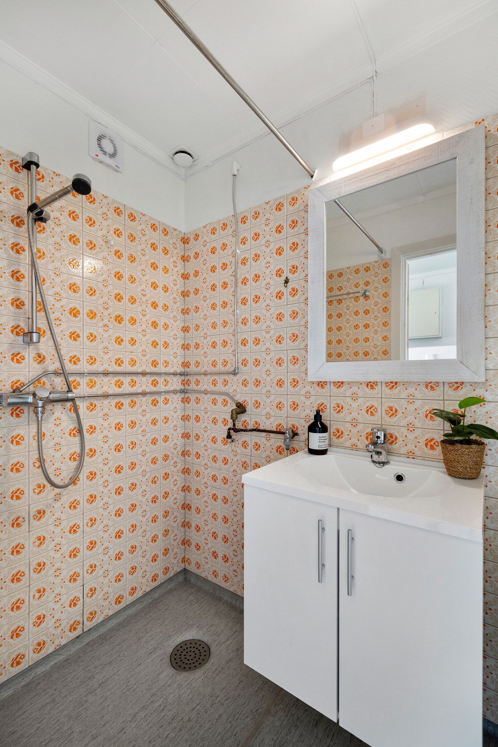 Badet er innredet med servant i baderomsinnredning, speil, dusj på vegg og wc Galleribilde