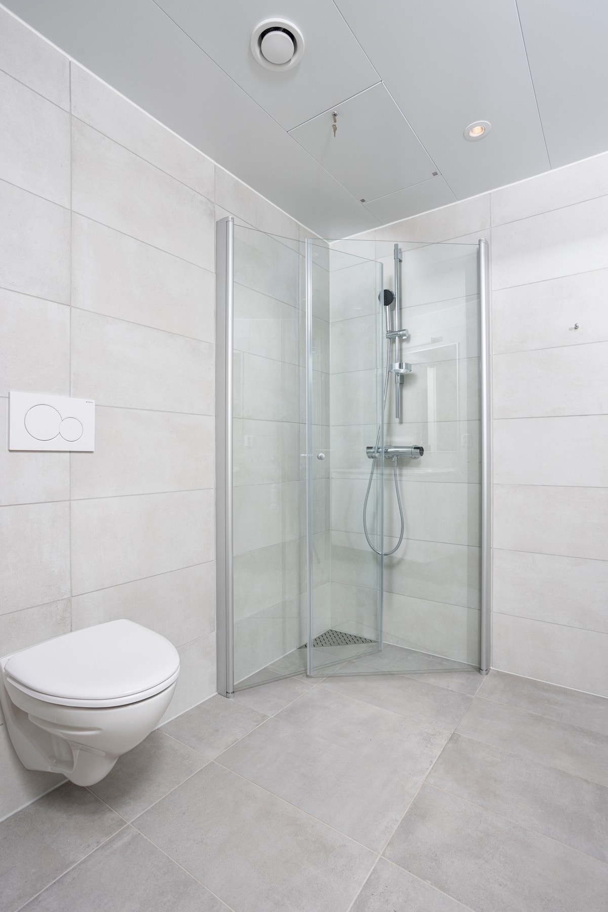 Moderne bad med lyse farger med gulvvarme, dusjvegger, wc og downlights. Galleribilde