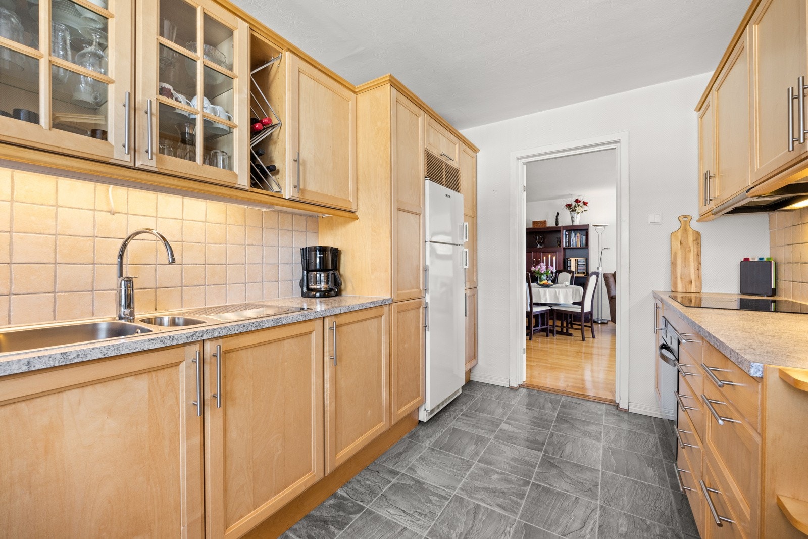 Kjøkkeninnredning langs to vegger med profilerte fronter, laminat benkeplate med kum og godt med både skap og skuffer. Galleribilde