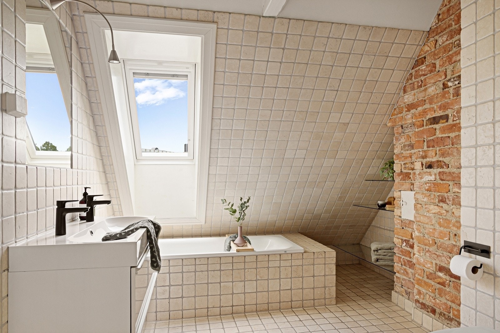 Badet på loftet er stort, ca. 10 m², med gjennomtenkte løsninger og behagelig gulvvarme. Innredningen består av servantskap med speil og belysning over og vegghengt toalett. Galleribilde