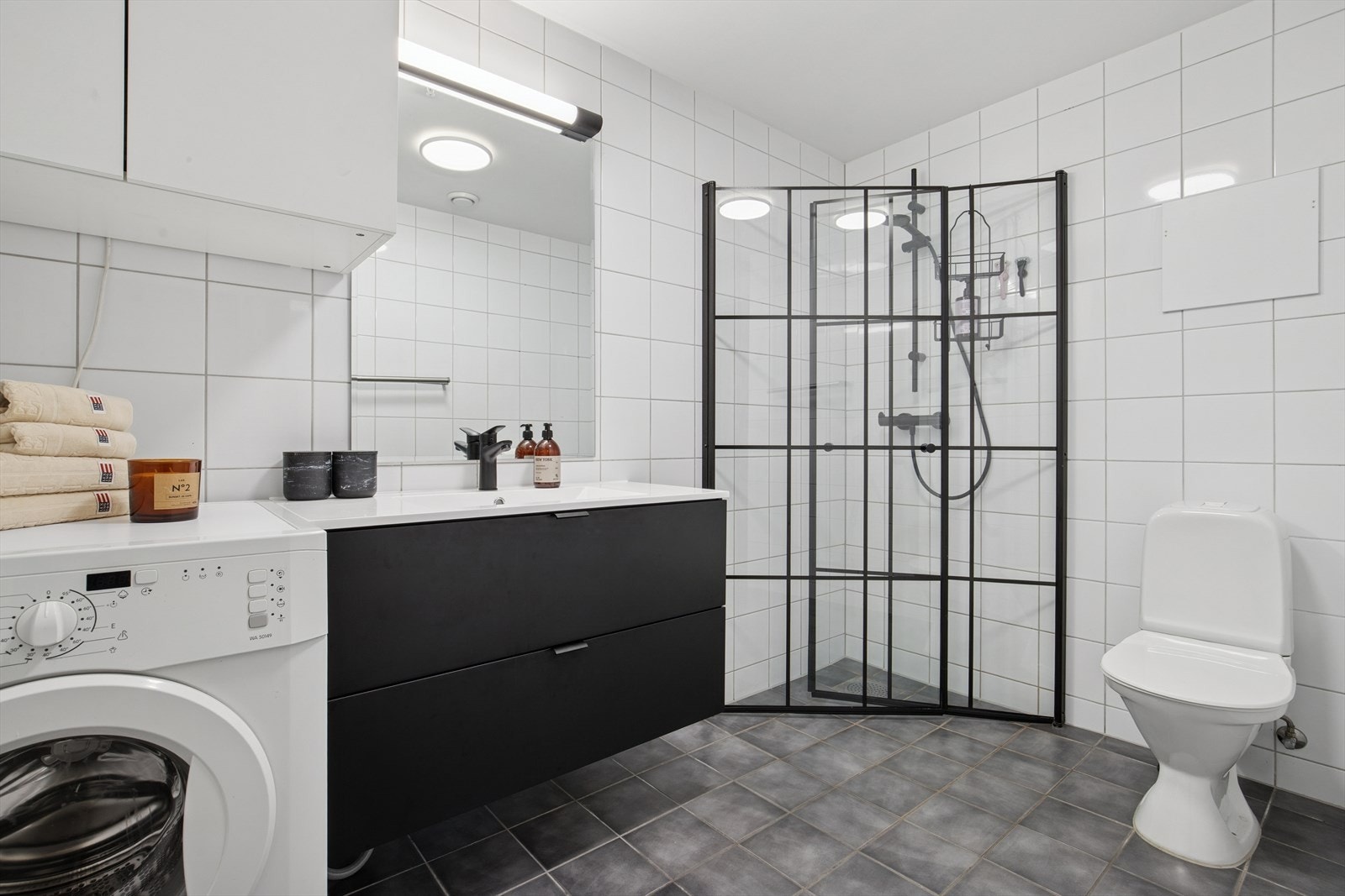 Badet fungerer som kombinert bad og vaskerom med fliser på vegger og gulv som har elektriske varmekabler som oppvarming. Galleribilde